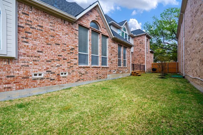 View of side yard of property with roof with shingles, brick siding, fence, and a lawn | Image 22