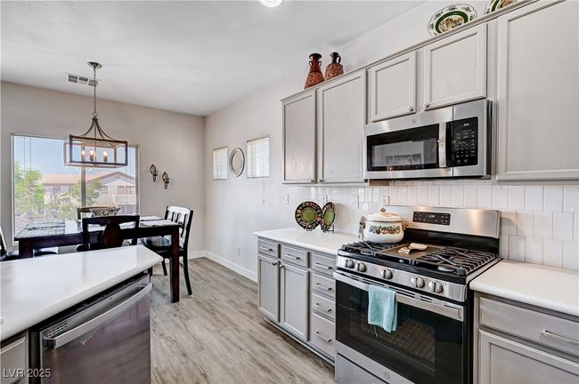 Kitchen featuring stainless steel appliances, a chandelier, light wood finished floors, and decorative backsplash | Image 5