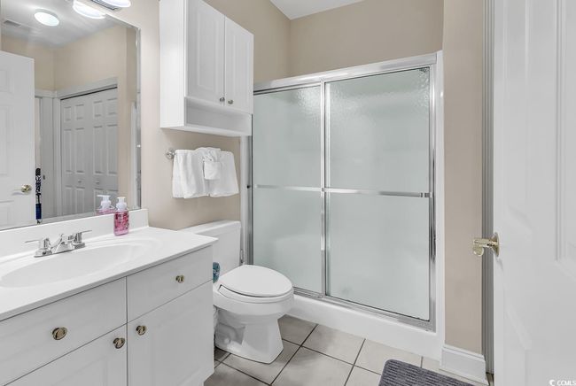 Full bathroom with toilet, tile patterned flooring, a stall shower, and vanity | Image 14