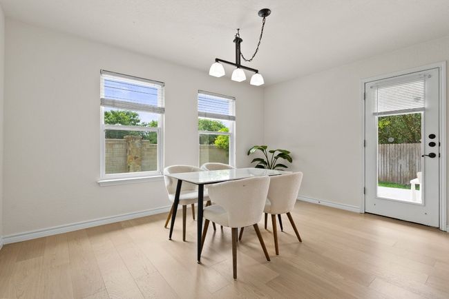 Dining room featuring plenty of natural light with view of the backyard, light wood-style flooring, and chandelier | Image 9
