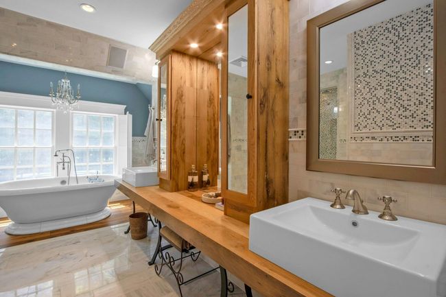 Full bathroom featuring tile walls, a freestanding tub, a sink, and a chandelier | Image 22