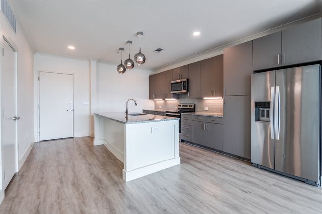 Kitchen with appliances with stainless steel finishes, decorative backsplash, light wood-type flooring, light stone counters, and recessed lighting | Image 7