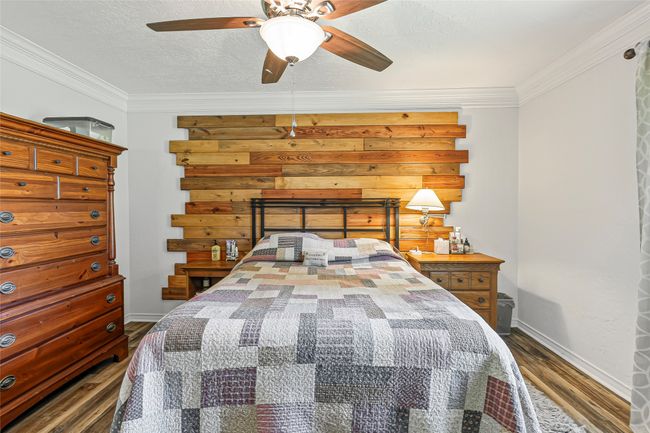Bedroom featuring dark wood-style flooring, crown molding, and ceiling fan | Image 15