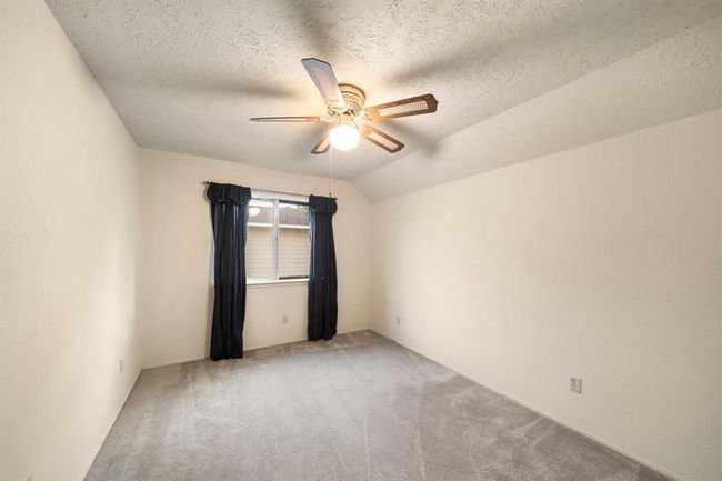 Upstairs secondary bedroom features soft neutral carpet, textured ceilings, and a ceiling fan for climate control. | Image 28