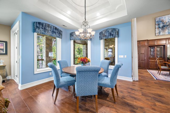 dining room with a notable chandelier, dark wood-style flooring, baseboards, and a tray ceiling | Image 24