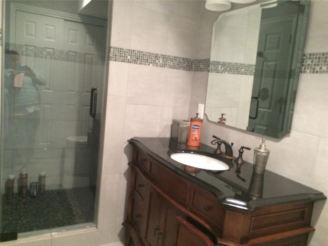 Bathroom with tile walls, vanity, and a shower stall | Image 12
