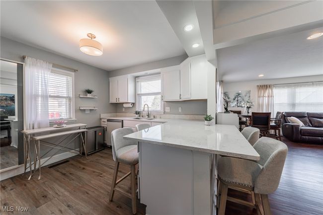 Kitchen with dishwasher, a sink, white cabinetry, and a breakfast bar | Image 12