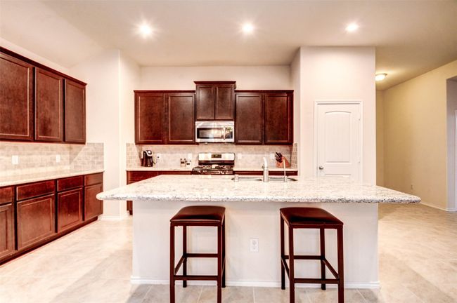 The large granite island offers a great space for friends and family to gather. | Image 5