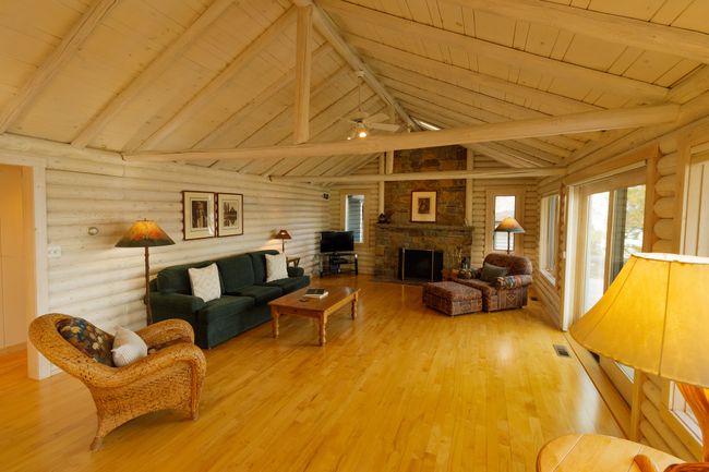 Living room with a stone fireplace, wood ceiling, hardwood / wood-style floors, and rustic walls | Image 24
