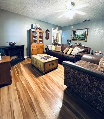 Living room featuring ceiling fan, a textured ceiling, and wood-type flooring | Image 3