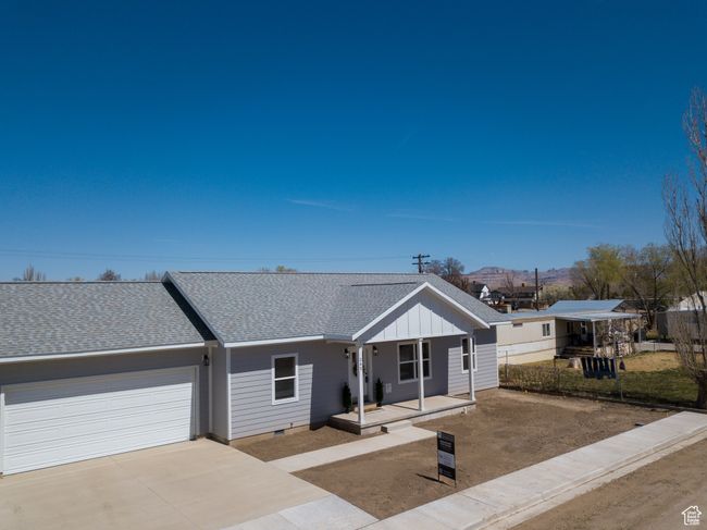 View of front of property with an attached garage, covered porch, board and batten siding, concrete driveway, and roof with shingles | Image 38