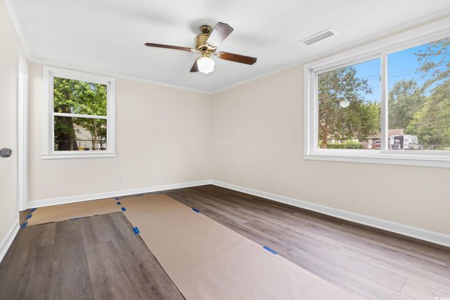 Empty room with wood finished floors, baseboards, healthy amount of natural light, ceiling fan, and crown molding | Image 28