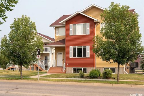 Multi-level exterior with red and yellow siding, white window trim, and white shutters | Card Image