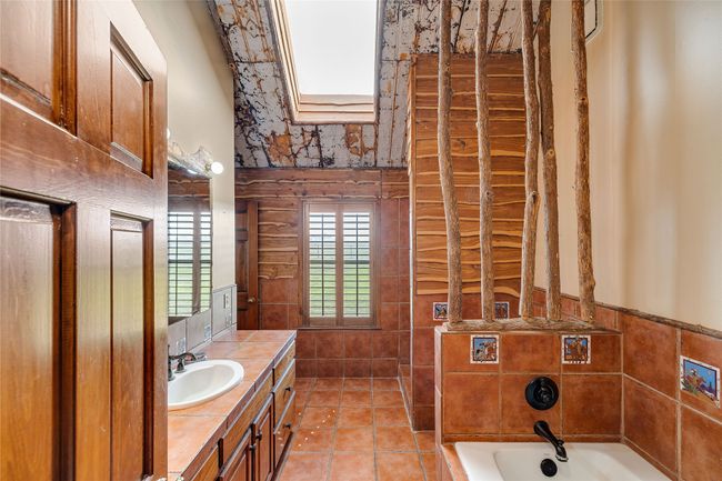 Full bathroom with vanity, a high ceiling, a garden tub, tile walls, and tile patterned flooring | Image 16