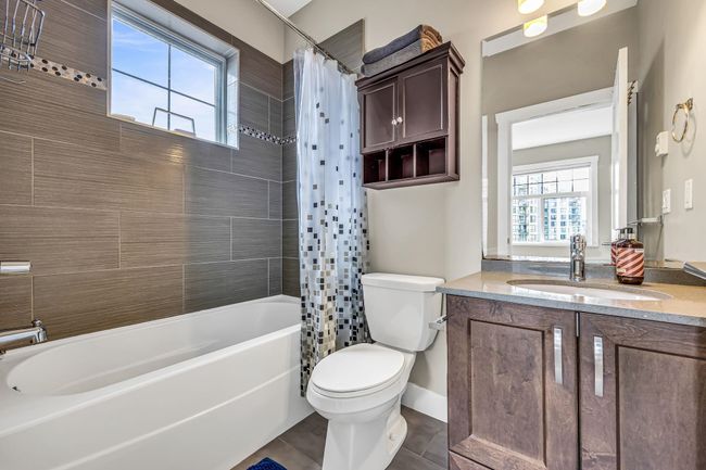 Full bathroom featuring toilet, vanity, shower / bathtub combination with curtain, tile patterned floors, and baseboards | Image 20