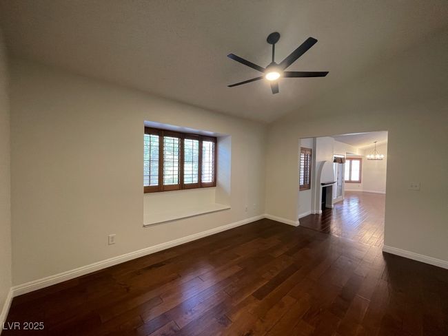 Empty room featuring a chandelier, plenty of natural light, dark wood finished floors, a ceiling fan, and lofted ceiling | Image 13