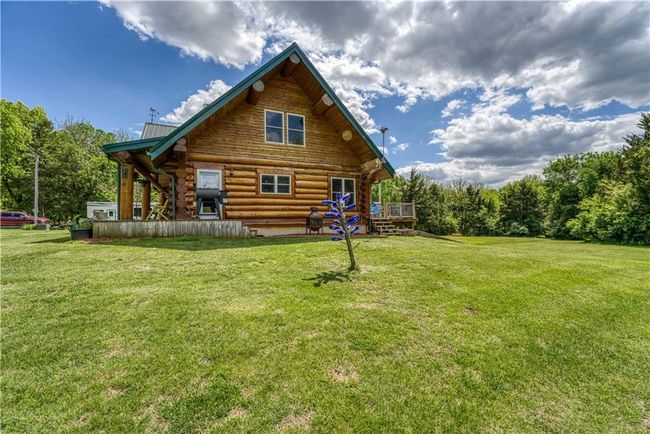 Back of house with log siding, a deck, and a lawn | Image 5