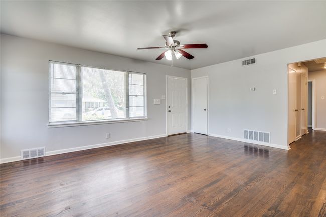 Unfurnished living room with dark wood-type flooring, visible vents, and a ceiling fan | Image 5