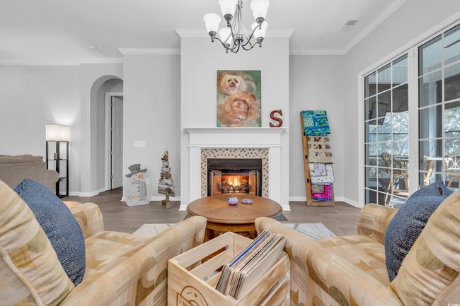 Living area with an inviting chandelier, arched walkways, crown molding, and wood finished floors | Image 19