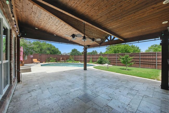 Large stone floored, covered back porch with lights & rails for privacy curtains. | Image 31