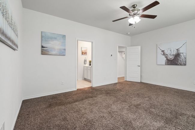 Primary Bedroom with light colored carpet, baseboards, ensuite bath, and ceiling fan | Image 17