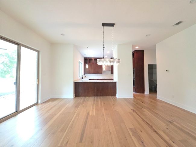 Kitchen with light countertops, open floor plan, light wood finished floors, a sink, and baseboards | Image 4