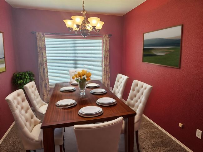 Carpeted dining space with a chandelier and baseboards | Image 7