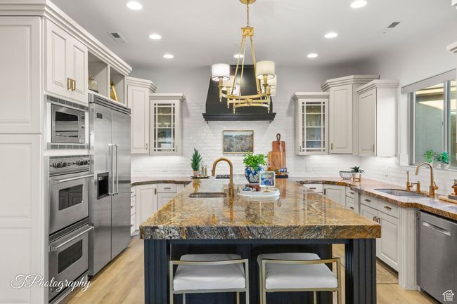 Kitchen with appliances with stainless steel finishes, a sink, an island with sink, decorative backsplash, and recessed lighting | Image 15