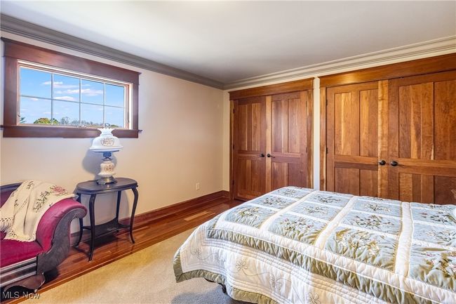 Bedroom featuring multiple closets, crown molding, baseboards, and wood finished floors | Image 34