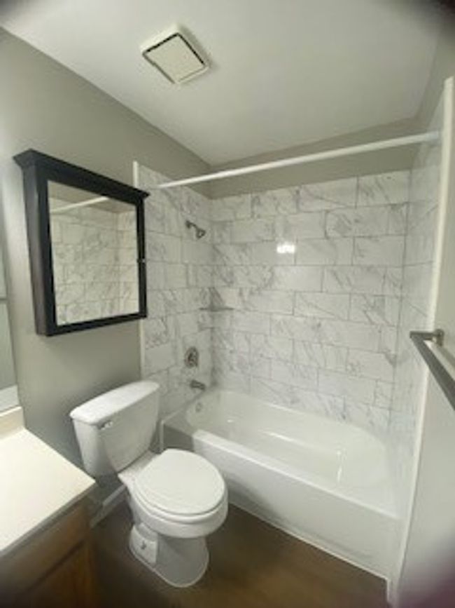 Full bathroom featuring bathing tub / shower combination, vanity, toilet, and wood finished floors | Image 33