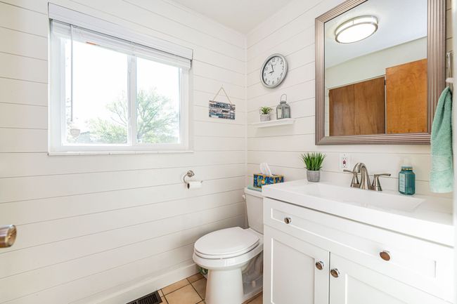 Bathroom featuring vanity, toilet, tile patterned floors, wood walls, and visible vents | Image 25