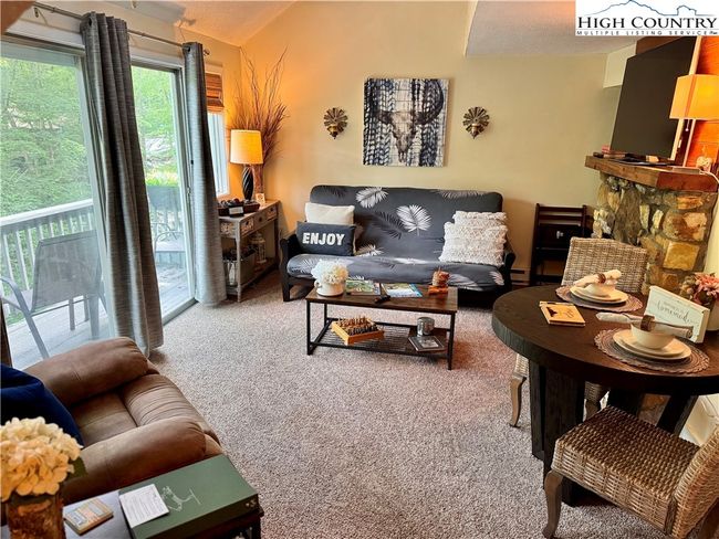 Open and bright living room overlooking a private balcony. This unit has cathedral ceilings and is impeccably clean and maintained. | Image 12