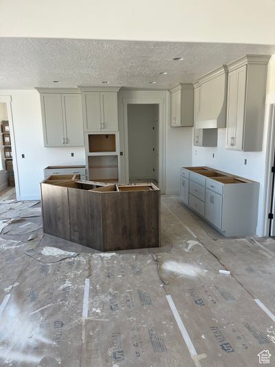 Kitchen featuring a textured ceiling, a kitchen island, and gray cabinetry | Image 2