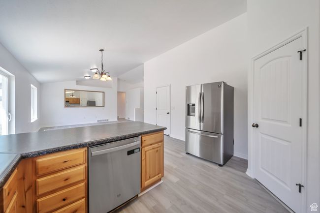 Kitchen with stainless steel appliances, vaulted ceiling, dark countertops, and a chandelier | Image 12