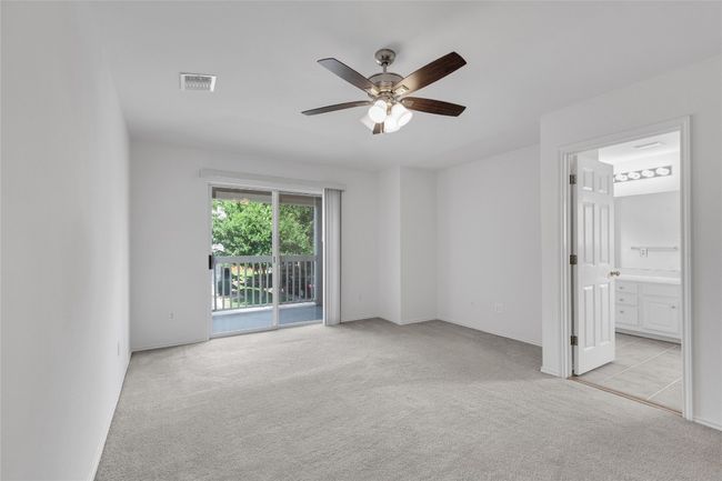 Unfurnished bedroom featuring access to outside, light colored carpet, ensuite bath, and a ceiling fan | Image 21
