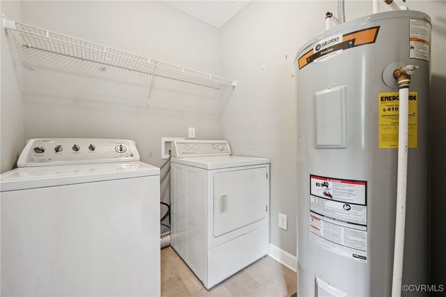 Laundry room featuring water heater, washer and clothes dryer, and light tile patterned floors | Image 19
