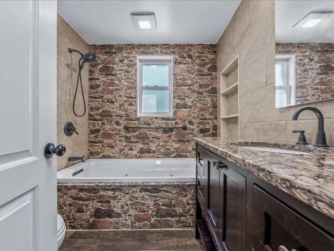 Bathroom featuring vanity, a combined bath / shower with jetted tub, toilet, and plenty of natural light | Image 15