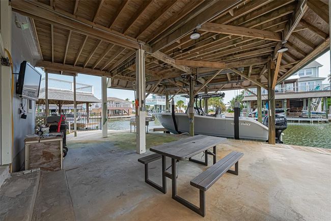 This covered dock area features a boat slip with a lift, a picnic table, and a TV, perfect for waterside relaxation and entertainment. The setting is ideal for boating enthusiasts with easy access to the water. | Image 33