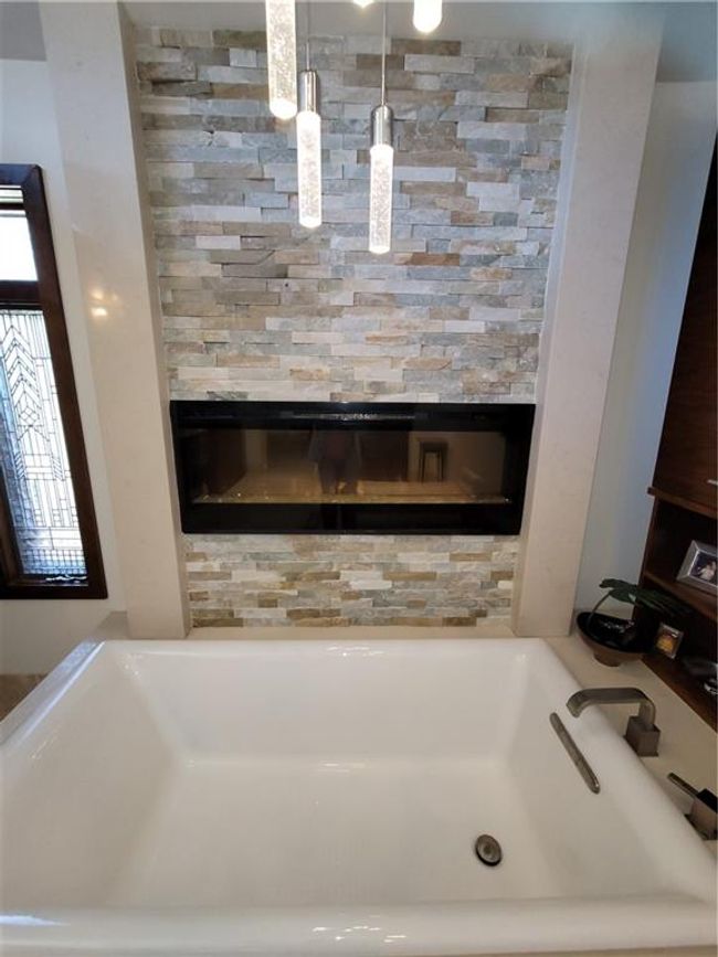 Full bath featuring a tub and a glass covered fireplace | Image 35