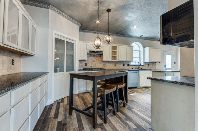 Kitchen featuring stainless steel dishwasher, dark wood-style floors, tasteful backsplash, and under cabinet range hood | Image 11
