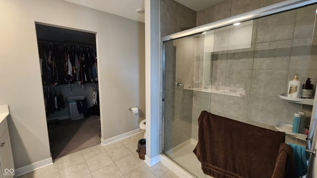 full bath with tile patterned flooring, a stall shower, a walk in closet, and vanity | Image 16