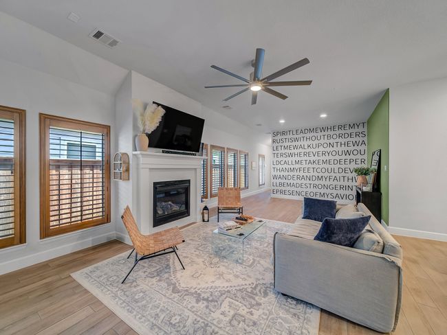 Living room with wood finished floors, a glass covered fireplace, and ceiling fan | Image 12