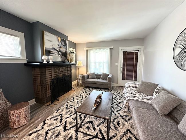 Living area featuring a brick fireplace, baseboards, wood finished floors, and plenty of natural light | Image 6