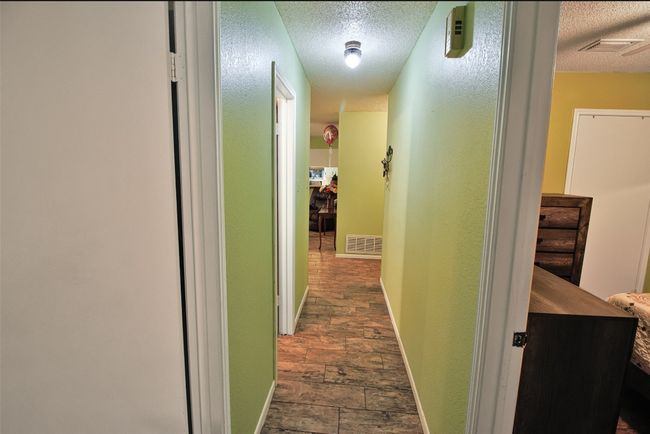 Corridor featuring a textured ceiling, baseboards, and visible vents | Image 9