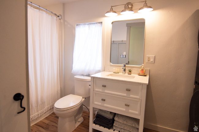 Bathroom featuring toilet, wood finished floors, vanity, and a shower with shower curtain | Image 21