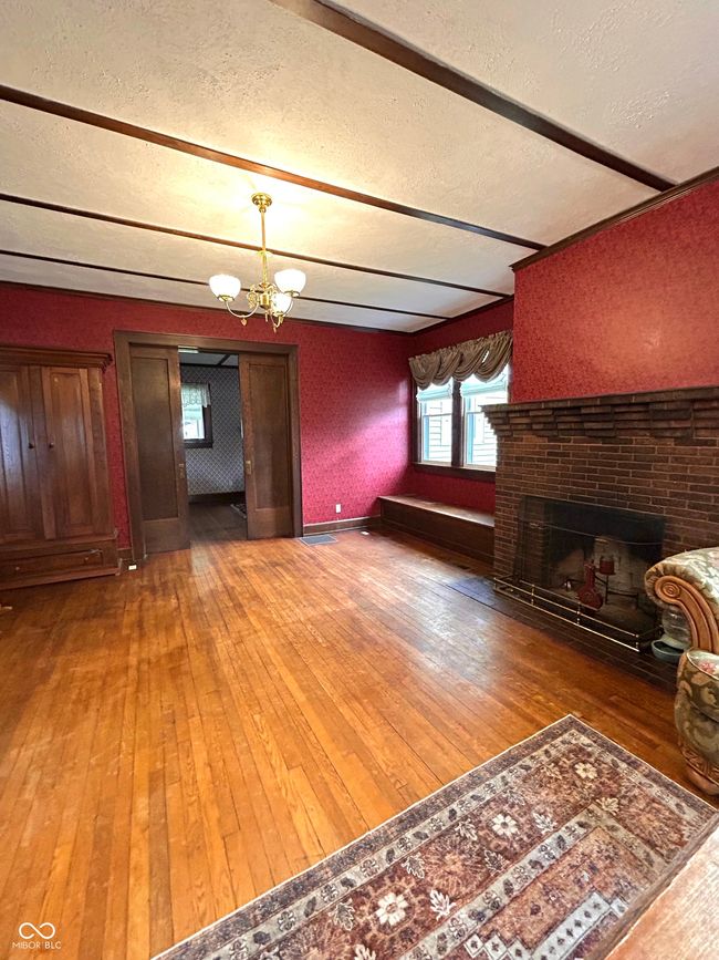 living room featuring light wood finished floors, an inviting chandelier, a brick fireplace, and a textured ceiling | Image 10
