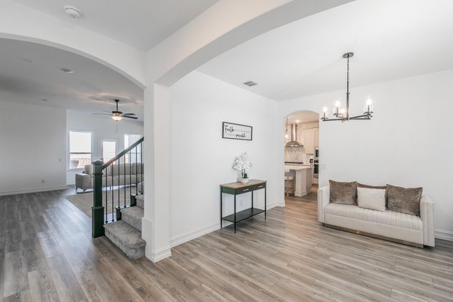 Living room featuring wood-type flooring and ceiling fan with notable chandelier | Image 4