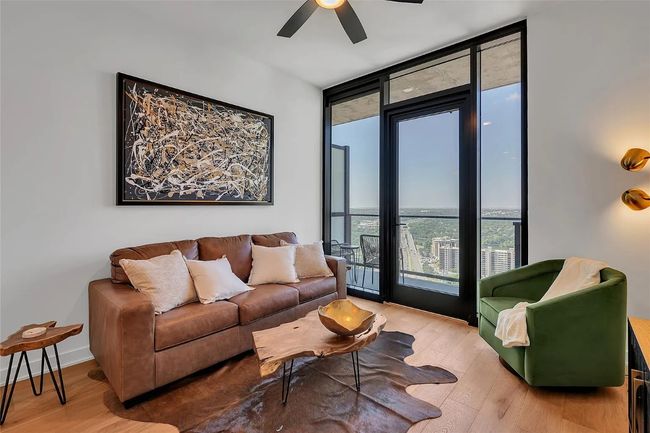 Living room with expansive windows, ceiling fan, and light wood finished floors | Image 6