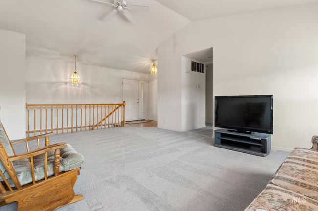 Carpeted living room featuring ceiling fan and vaulted ceiling | Image 4