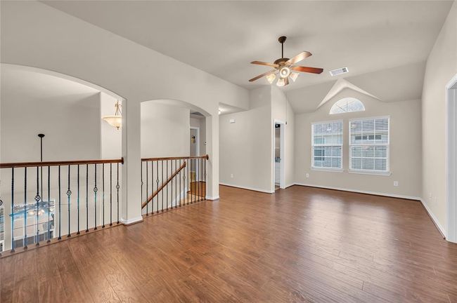 Spacious game room featuring elegant wood flooring, abundant natural light, and a stylish ceiling fan—perfect for entertainment and relaxation. | Image 36